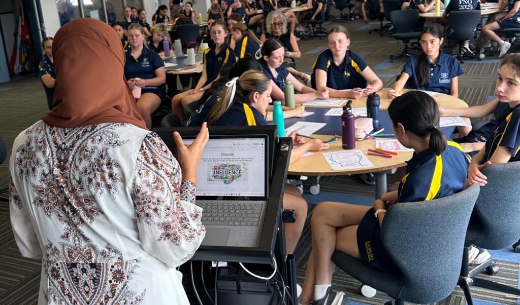 A TFH presenter who is a Muslim woman shares a story with a classroom of high school students
